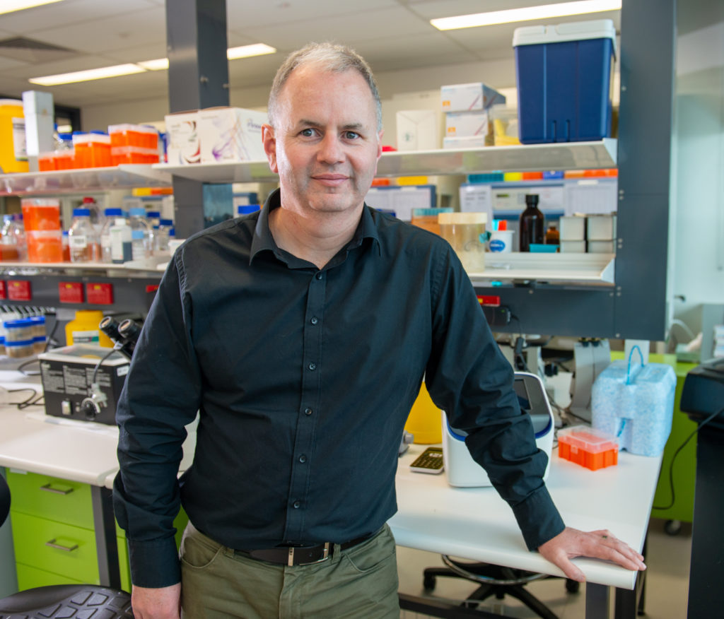 Male cancer researcher standing in lab